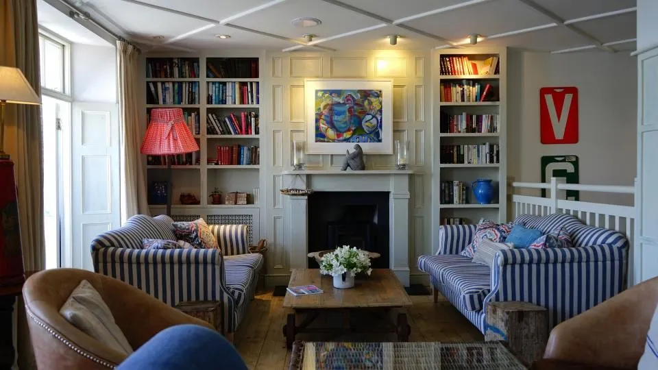 A sunny living room with a sofa, a rug and shelves of books