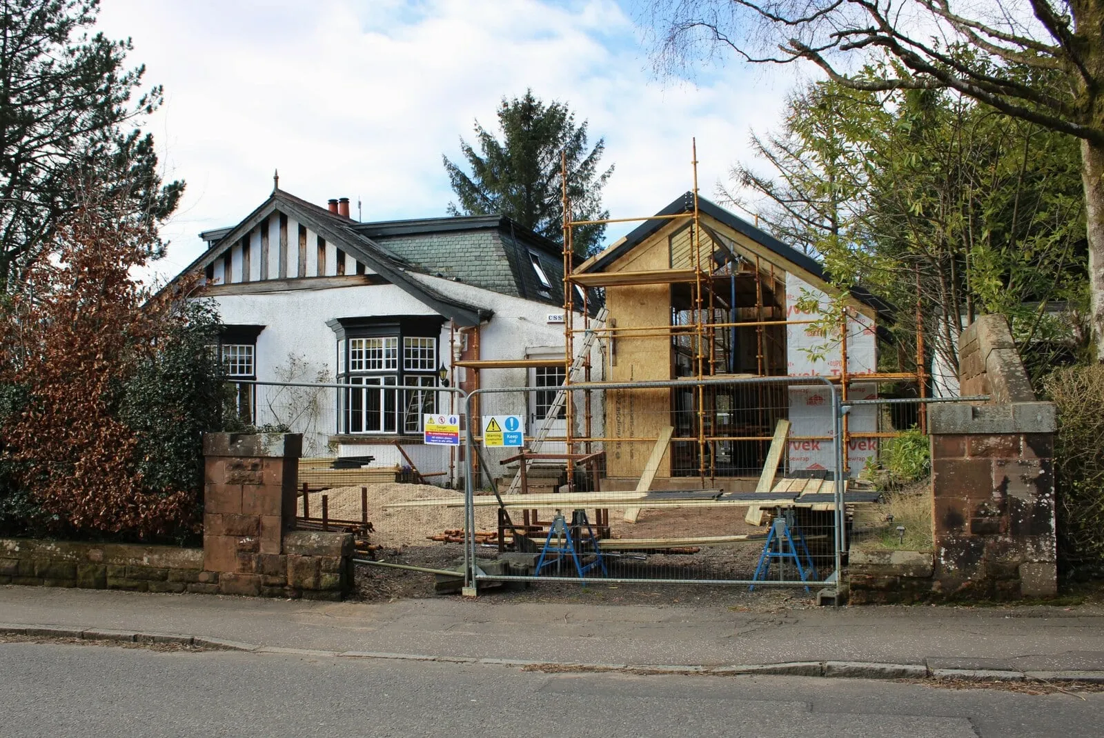 Timber-framed side extension surrounded by scaffolding next to a white cottage